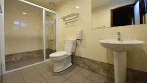 Un baño con inodoro, lavamanos y cabina de ducha de vidrio.