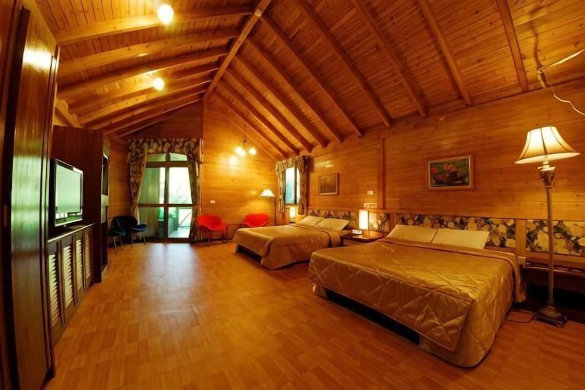 A wooden interior with two beds, a TV, and a dining area.
