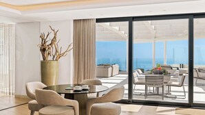 A modern, well-lit room with a large glass door leading to a balcony with a view of the ocean. There is a round table with chairs and a potted plant. - Palo Alto 6 | Marbella Panoramic Views Luxury (Málaga)
