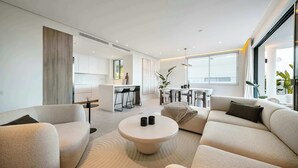 A modern living room with a sofa, a coffee table, and a kitchen area in the background. - Palo Alto 6 | Marbella Panoramic Views Luxury (Málaga)