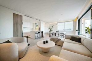 A modern living room with a sofa, a coffee table, and a kitchen area in the background. - Palo Alto 6 | Marbella Panoramic Views Luxury (Málaga)