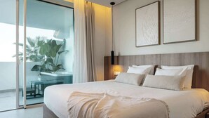 A modern hotel room with a large bed, a bedside table, a nightstand, a potted plant, and a view of the outside balcony. - Palo Alto 6 | Marbella Panoramic Views Luxury (Málaga)