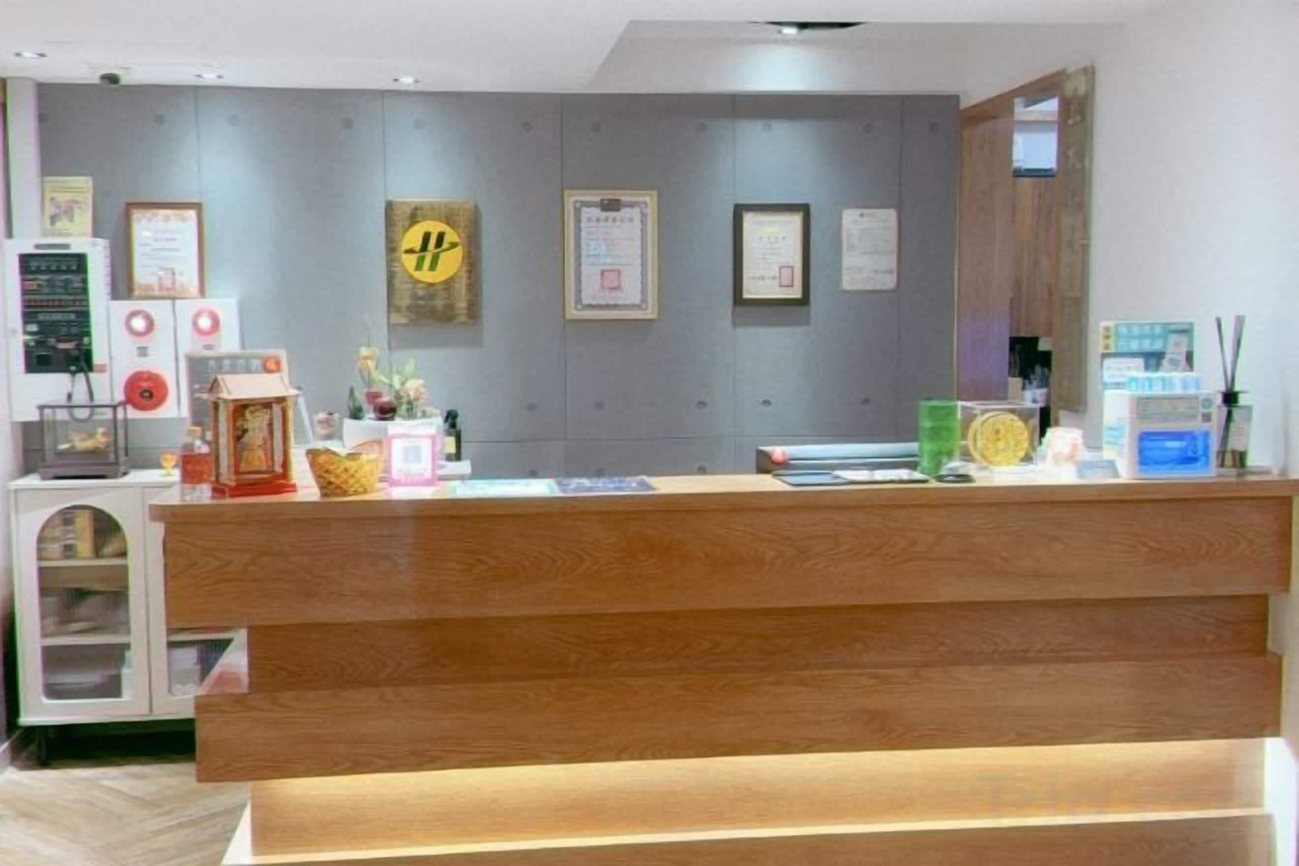 A reception desk with a wooden counter, a small refrigerator, and a wall with framed certificates.