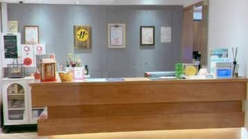 A reception desk with a wooden counter, a small refrigerator, and a wall with framed certificates.