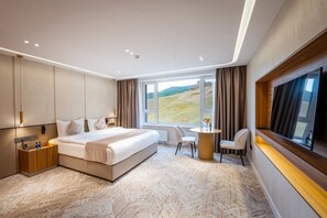 Une chambre dâhĂŽtel moderne, dotĂ©e dâun grand lit, dâun bureau et offrant une vue sur un paysage.