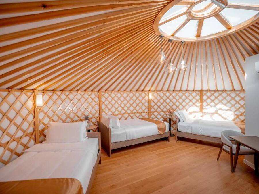 Una habitación estilo yurta con dos camas, un escritorio y una claraboya circular.