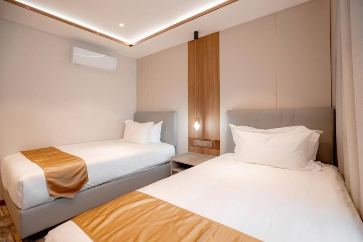 Una habitación de hotel con dos camas, una mesita de noche y un aire acondicionado de pared.