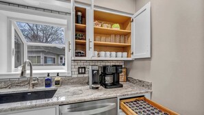 A kitchen with a granite countertop, a coffee maker, a dishwasher, and a drawer with muffin tins. - Portage Lakes Retreat with Boat & Views (New Franklin)