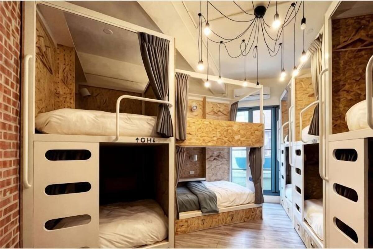 Une chambre avec un lit superposé, un intérieur en bois, un luminaire au plafond et une fenêtre.