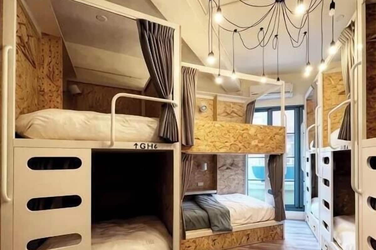 Une chambre avec un lit superposé, un lustre, des murs en bois et une fenêtre.