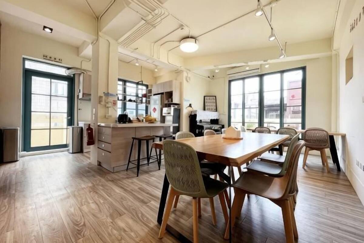 Une cuisine spacieuse dotée d’un grand îlot central, de planchers en bois et d’un coin repas avec des chaises et une table.