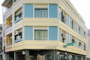 Un edificio de varios pisos con fachada plana, balcones y unidades de aire acondicionado.