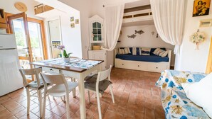 Une pièce confortable avec une table à manger, des chaises, un canapé et un lit superposé.