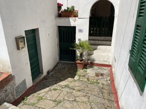 A narrow courtyard with a stone floor, a green door, and a potted plant. - Le Ginestre di Campo - Le Ginestre di Campo (Marina di Campo)