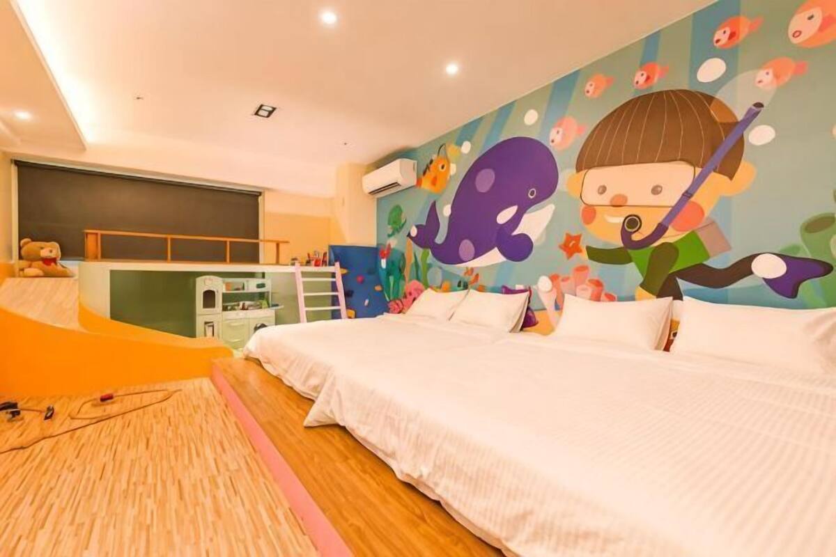 A bedroom with a bed, a desk, and a colorful mural on the wall.