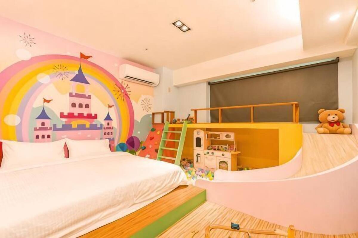 A child's bedroom with a bed, a play area, and a teddy bear.
