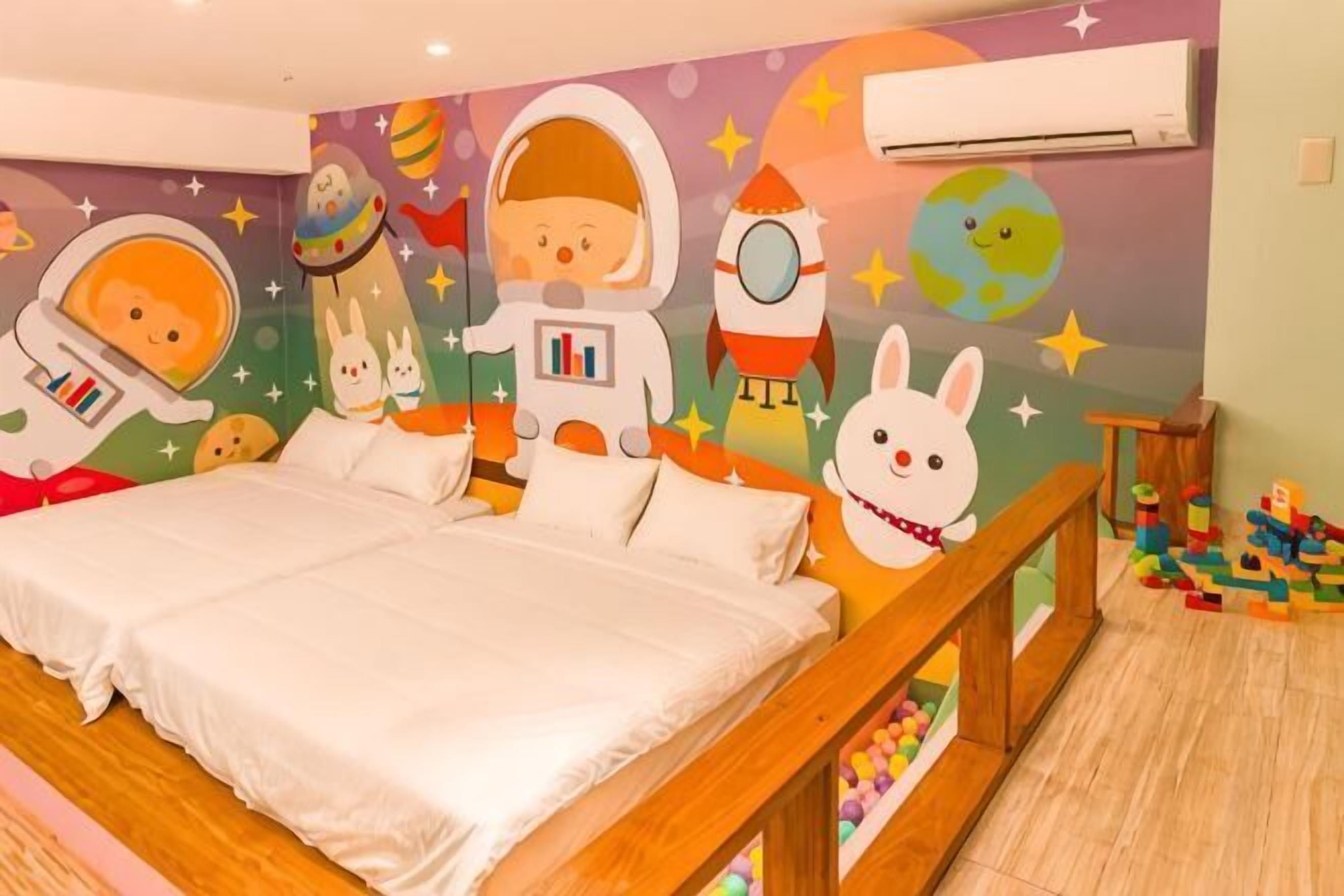 A children's room with a bed, a wall mural of astronauts and a rabbit, and a wooden bench.