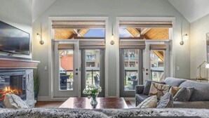 Un vaste espace de vie doté d’une cheminée, d’un canapé et d’une table basse. Deux portes donnent sur un espace extérieur.