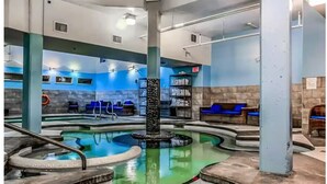 Un espace piscine doté de sièges disposés tout autour, d’un élément décoratif central avec de l’eau et d’un mur en pierre.