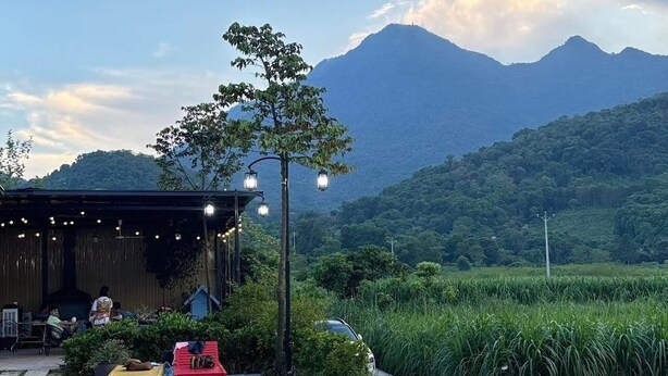A swimming pool with a pink flamingo float, surrounded by lush greenery and a mountainous backdrop. - Le Soleil Ba vi (Hanoi)