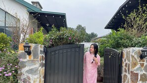 A gated entrance with a stone wall, a decorative lantern, and a basket of flowers. - Le Soleil Ba vi (Hanoi)