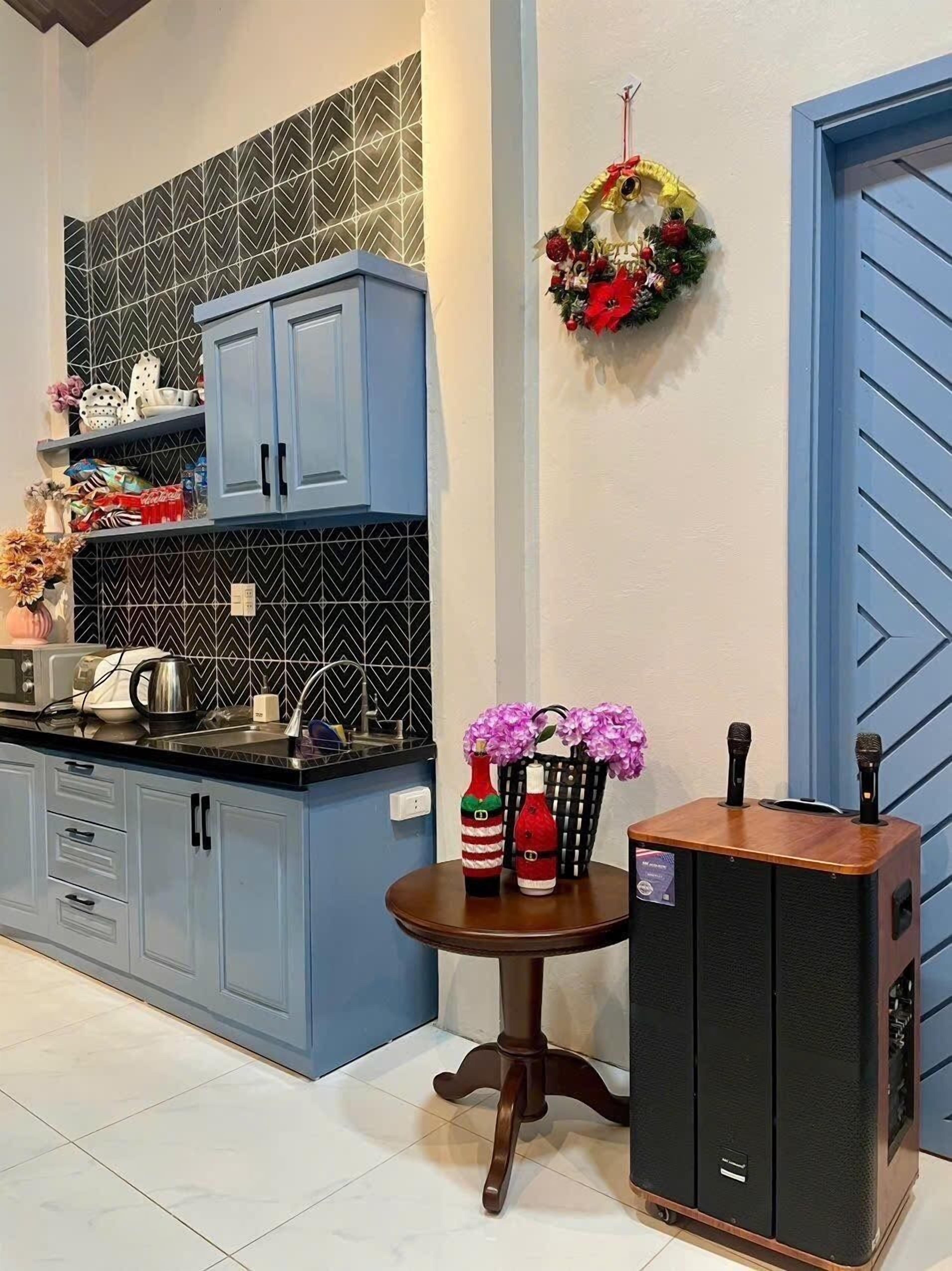 Une cuisine avec des armoires bleues, un comptoir noir et une guirlande décorative accrochée au mur.