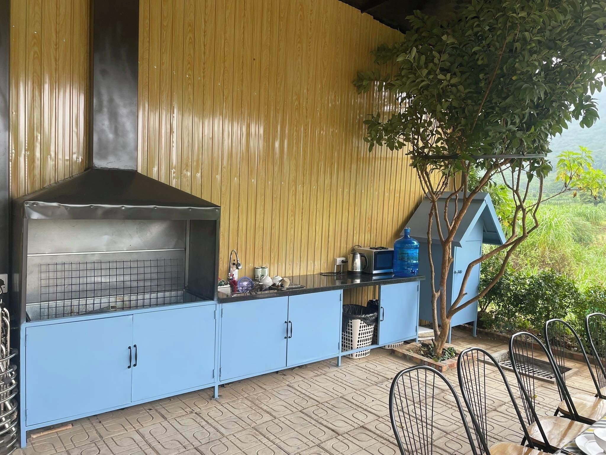 Una cocina exterior con una parrilla, armarios azules y un dispensador de agua.