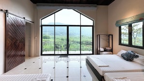 A bedroom with two beds, a large window with a view of greenery, a ceiling fan, and a wooden ceiling. - Le Soleil Ba vi (Hanoi)