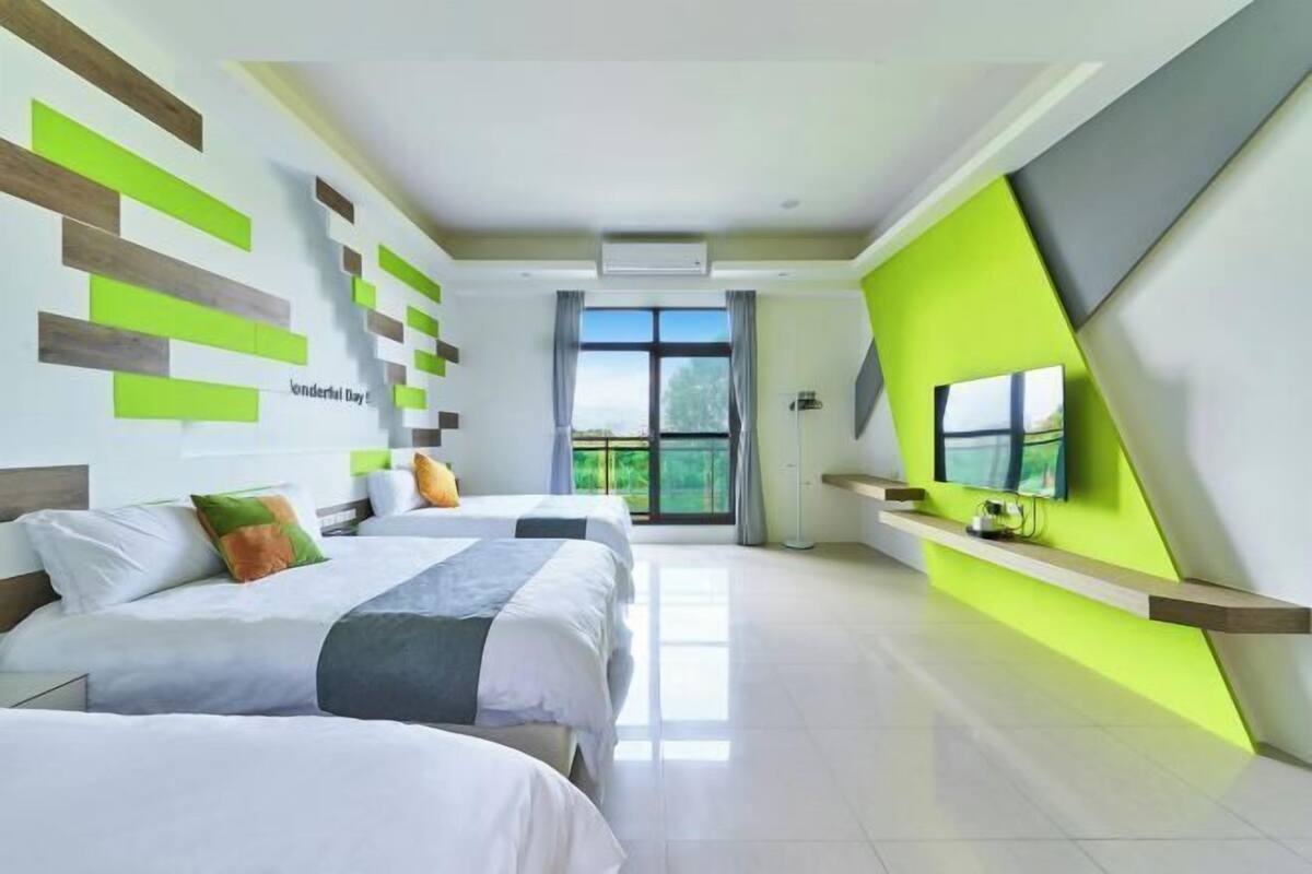A modern hotel room with two beds, a large window, and a TV on a built-in shelf.