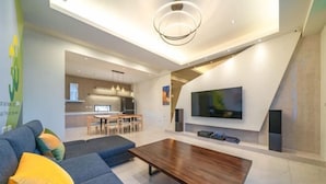 Una sala moderna con un sofá, una mesa de centro de madera y un televisor de pantalla plana montado en la pared.