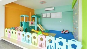 Zona de juegos infantiles con un tobogán, estructura de escalada y un coche de juguete.
