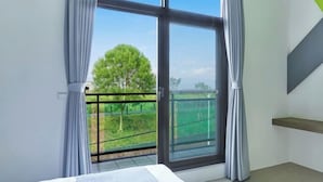 Un dormitorio con un ventanal grande, una cama y vistas a un paisaje verde.