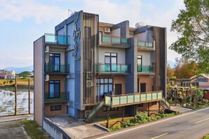 A multi-story hotel with balconies, a staircase, and a view of a body of water. - Xiangyue 38 Homestay (Yilan)