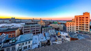 A cityscape with a mix of historical and modern buildings, including a large industrial facility in the background. - Double room river view (Québec)