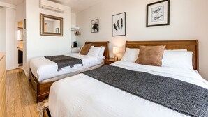 A hotel room with two beds, a mirror, framed artwork, and a wooden floor. - Double room river view (Québec)