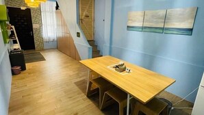 A compact kitchen with a wooden table and chairs, a staircase, and a wall-mounted artwork. - Iron shop Fuqiankan (Tainan)