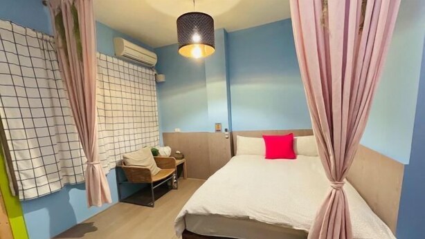 A bedroom with a bed, a chair, a small table, and a hanging light fixture. - Iron shop Fuqiankan (Tainan)
