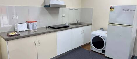 A compact kitchen with a toaster, kettle, microwave, and a small washing machine.