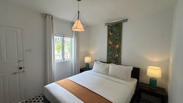 Ein Hotelzimmer mit einem Bett, zwei Nachttischen mit Lampen, einem Fenster mit Vorhängen, einer Tür und einem gemusterten Boden.