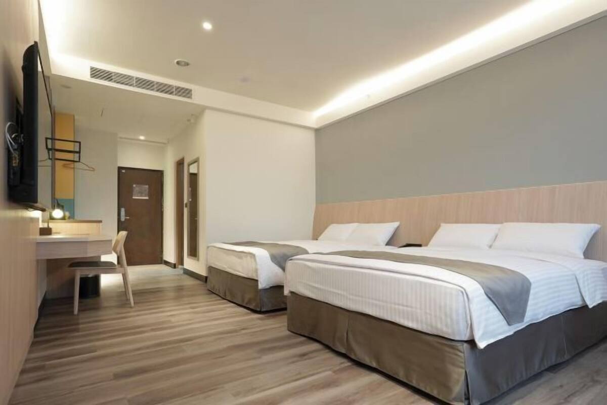 Une chambre d’hôtel avec deux lits, un bureau, une chaise et un téléviseur.