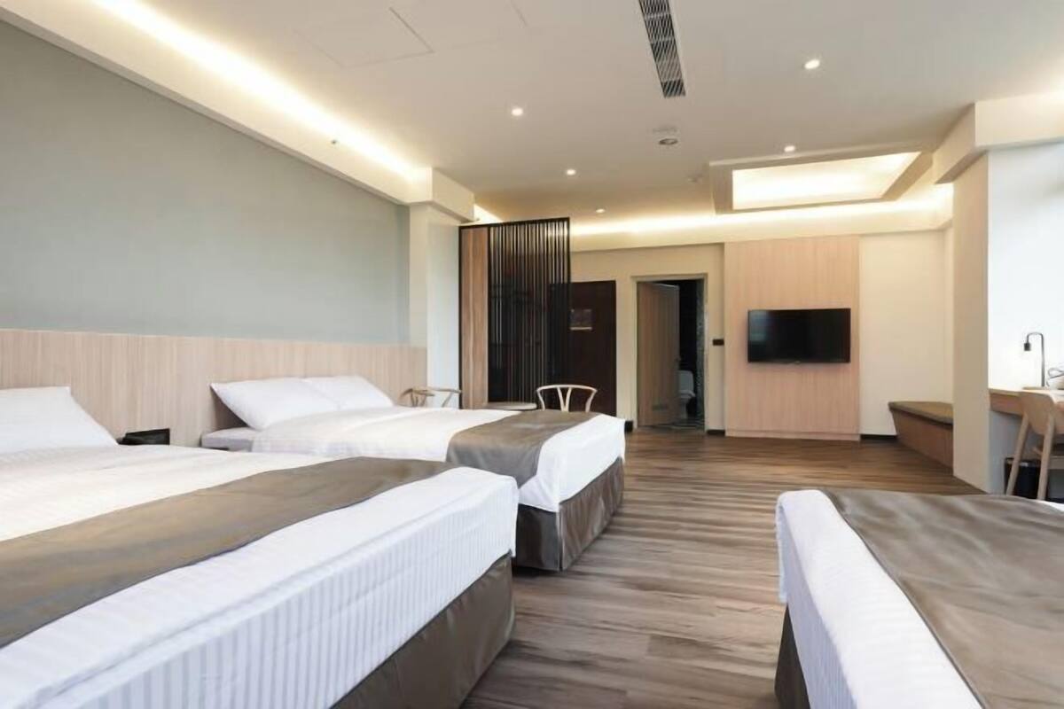 Une chambre d’hôtel avec trois lits, une télévision et un bureau.