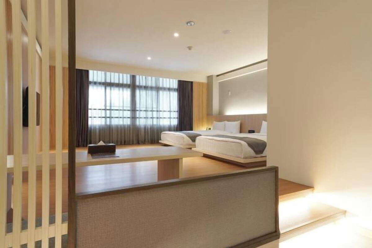 Une chambre d’hôtel moderne, dotée d’un grand lit, d’un bureau et offrant une vue sur la ville grâce à de larges fenêtres.