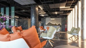 Un hall d’entrée moderne doté d’espaces de détente, d’un sol en marbre et d’un mur décoratif orné d’un motif de montagne.