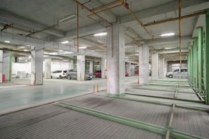 Un parking souterrain à plusieurs niveaux, avec des piliers en béton et quelques voitures garées.