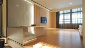 Une chambre moderne dotée d’un coin salon intégré, d’un téléviseur à écran plat et de grandes fenêtres.