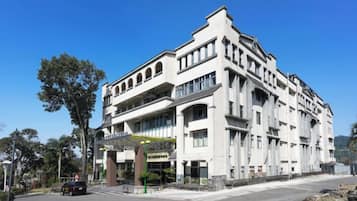 A large, multi-story building with a prominent entrance and a balcony on the second floor.