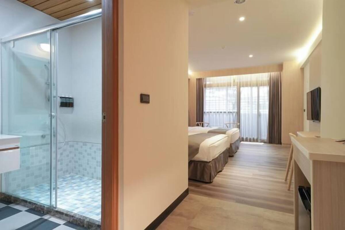 Une chambre d’hôtel équipée d’une douche, d’un lit, d’un bureau et d’une télévision.