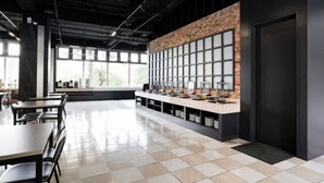 Un restaurant moderne avec un long comptoir, un sol carrelé et de grandes fenêtres.