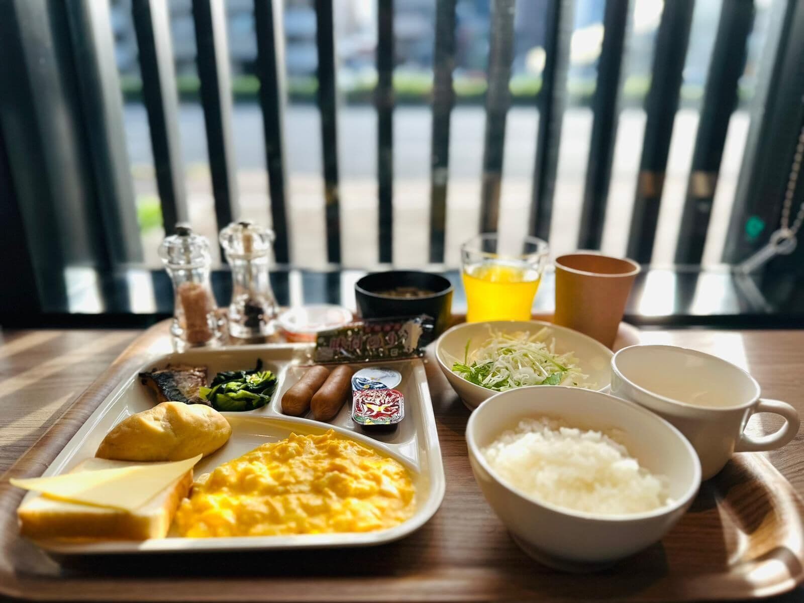 A meal tray with various dishes including rice, eggs, and vegetables, along with condiments and drinks.