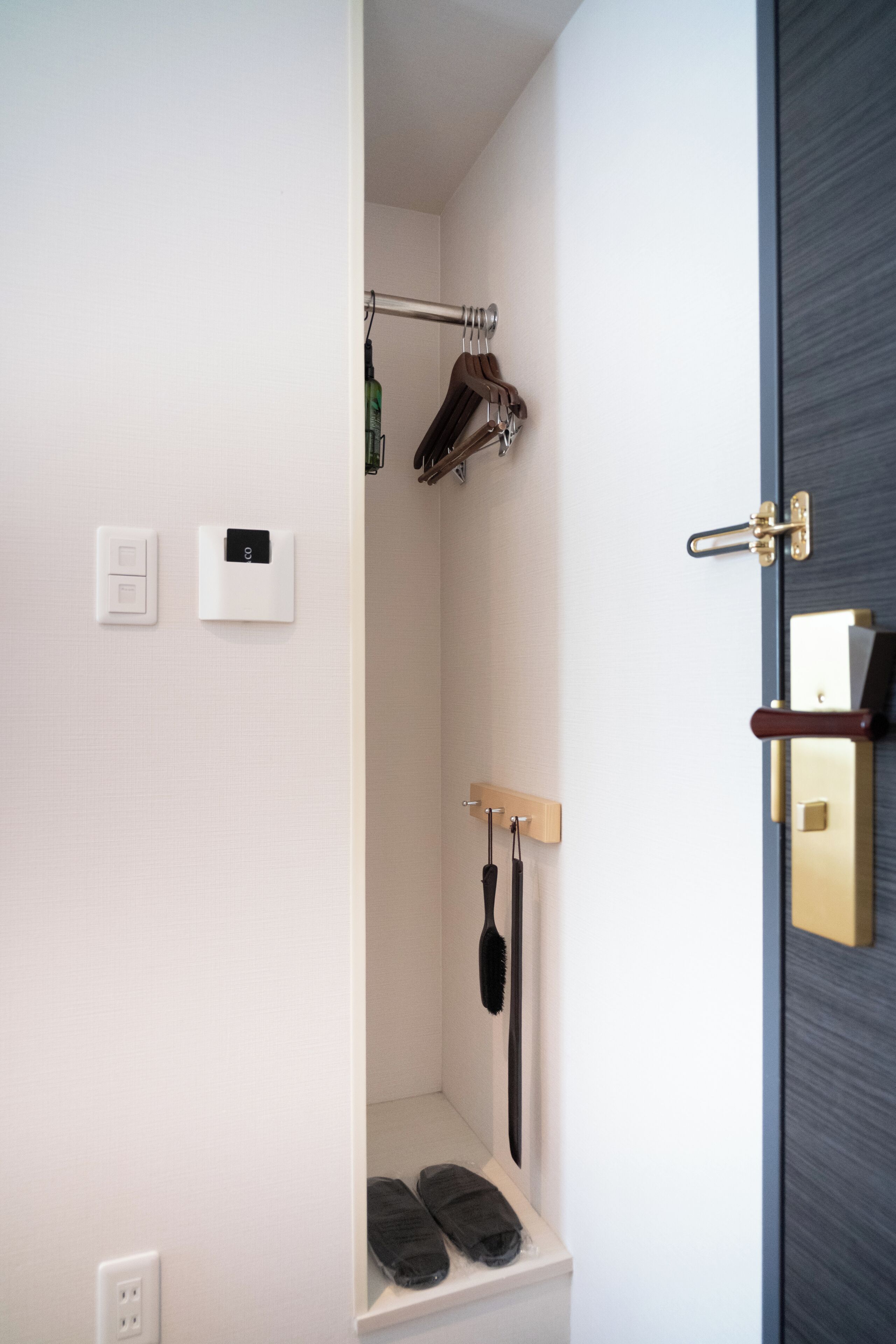 Un baño con ducha, toallero, estante para zapatos y una puerta con cerradura.